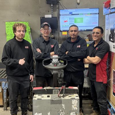 Quatre hommes posant dans un atelier de mécanique.