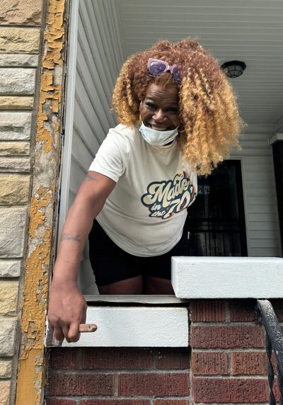 Woman with curly hair leaning on a porch railing.