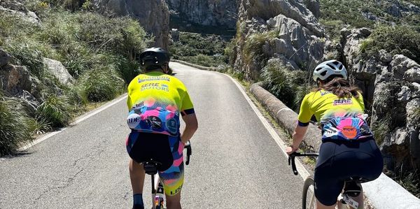 Two cyclists riding uphill on a mountain road.