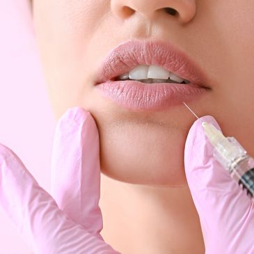 Close-up of lip injection procedure with needle and gloves.