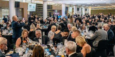 Elegant formal dinner event with many guests seated at tables.