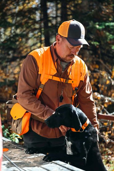 Hunter with his black dog in a forest setting.