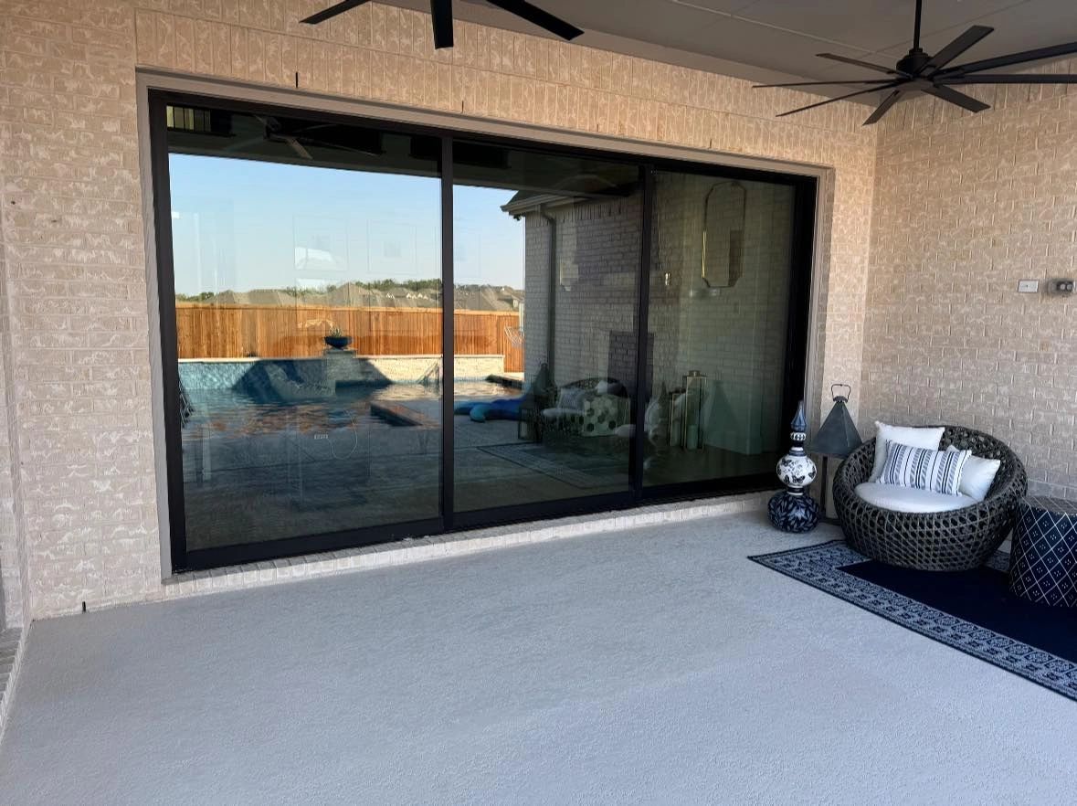 Cozy outdoor patio with wicker chair and large sliding glass doors.
