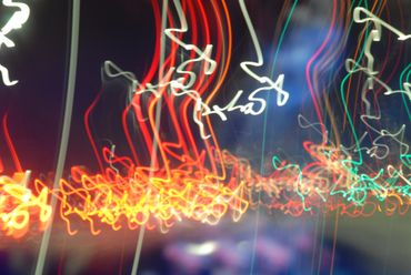 Abstract light trails in various colors against a dark background.