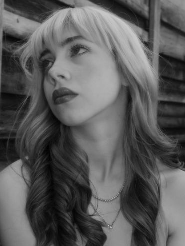 Black and white portrait of a woman with curled hair looking thoughtfully away.