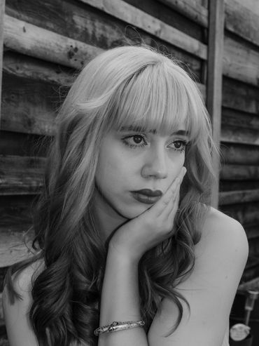 Black and white portrait of a thoughtful young woman resting her face on her hand.