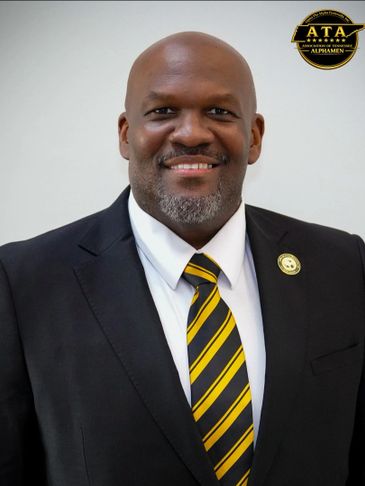Smiling man in suit with yellow and black striped tie.