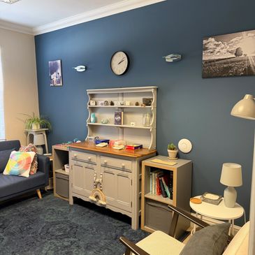 Cozy living room with blue accent wall, vintage cabinet, and comfortable seating.