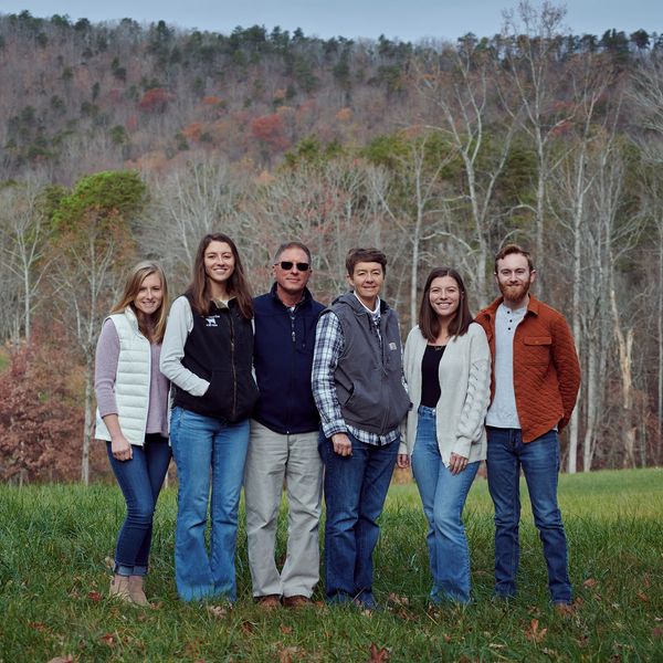 The Newsome family standing in a field on the property