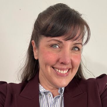 woman in a striped shirt and blazer smiling.
