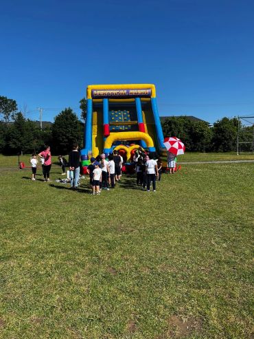Children lined up for a large inflatable slide outdoors.