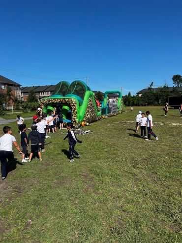 Children playing on a large inflatable obstacle course outdoors.