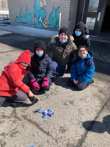 Kids playing with a small drone outside.