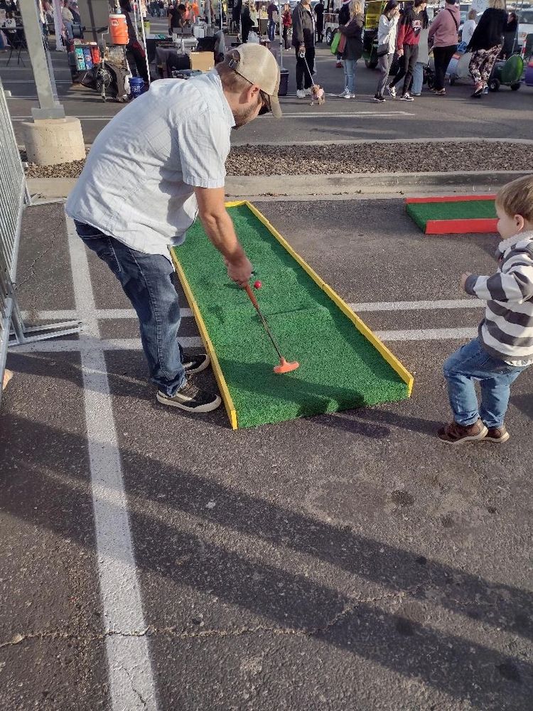 A child cheers with excitement as their dad putts, creating a joyful mini golf memory.