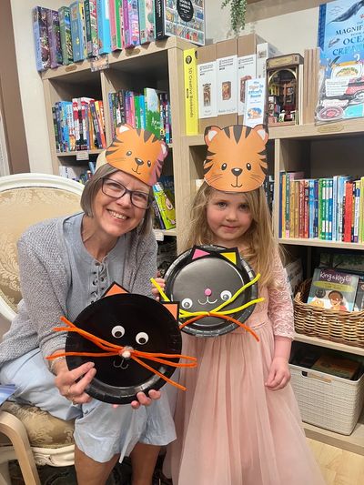 Woman and girl wearing cat hats holding cat crafts.