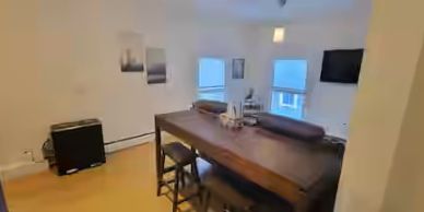 Apt 4 cozy dining area with wooden table and TV.