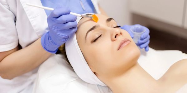 A woman receives a facial treatment with a brush while lying down.
