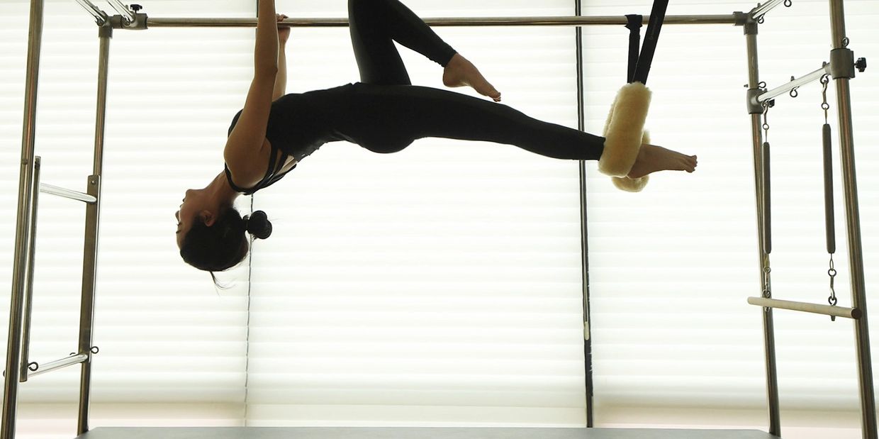 Woman performing a Pilates exercise on a reformer machine.