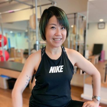 Smiling woman in black Nike tank top at a gym.