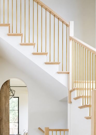 Modern staircase with gold railings and wooden steps.