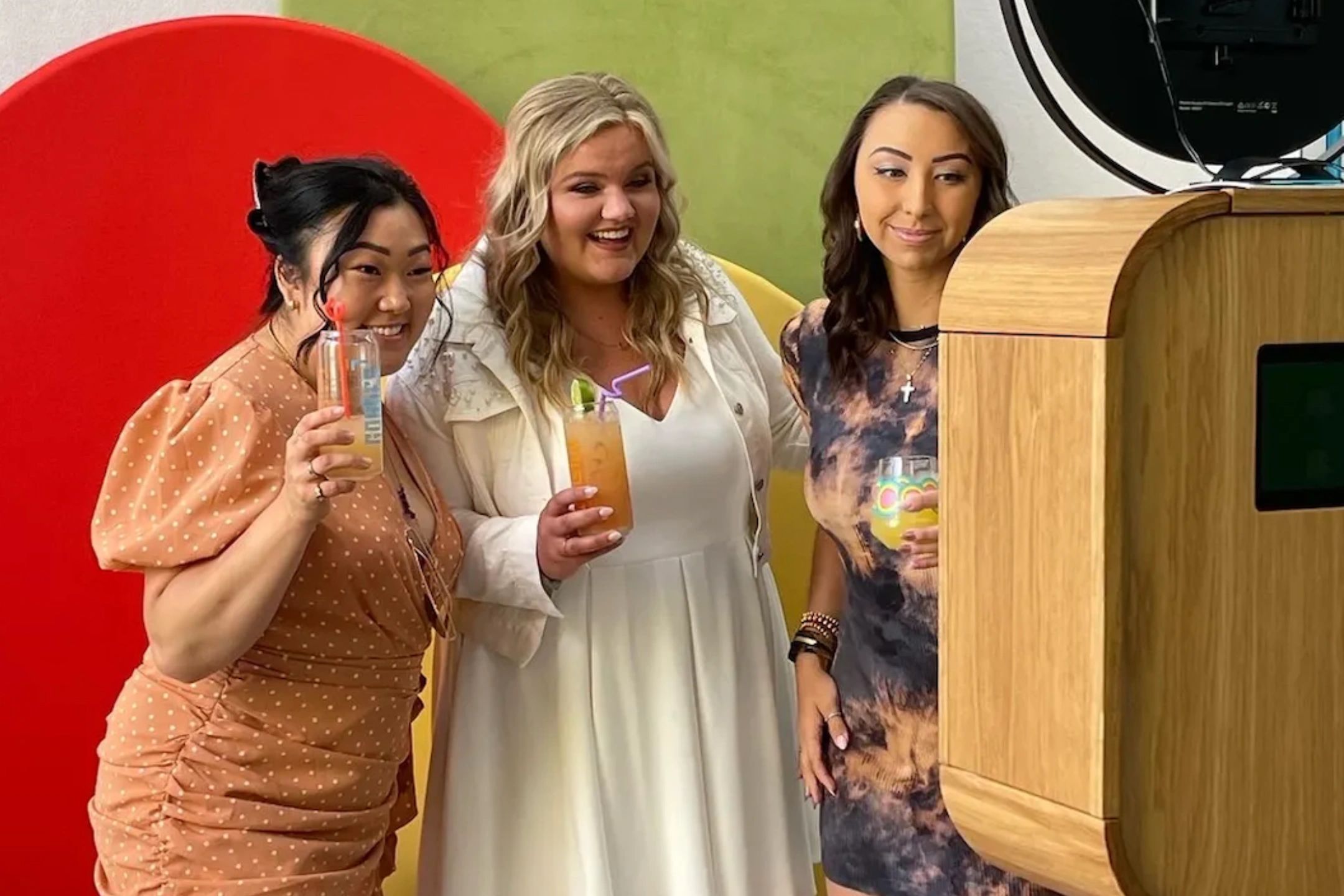 3 girls smiling in front of an open photo booth at a wedding party in Fairbanks.