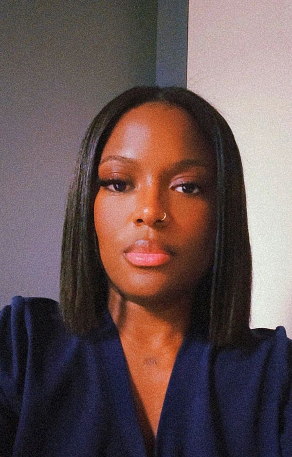 A woman with straight hair and a nose ring wearing a dark blue top.