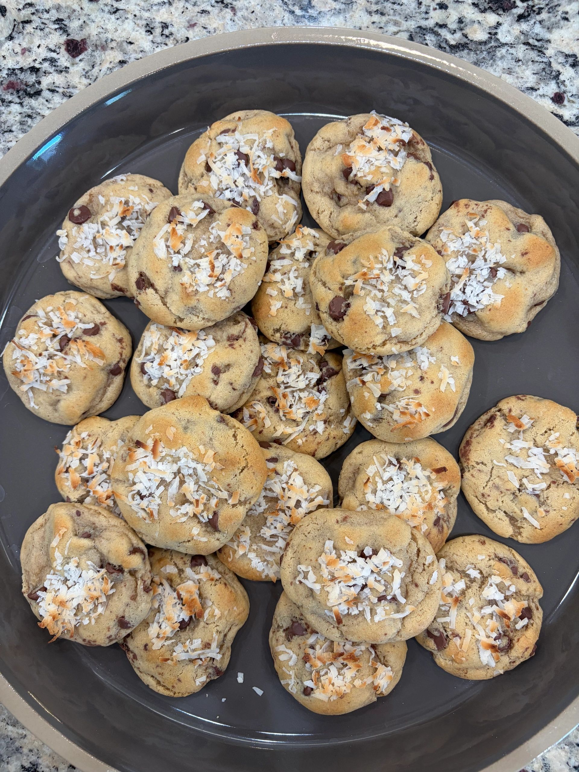 Plate of chocolate chip cookies topped with toasted coconut flakes.