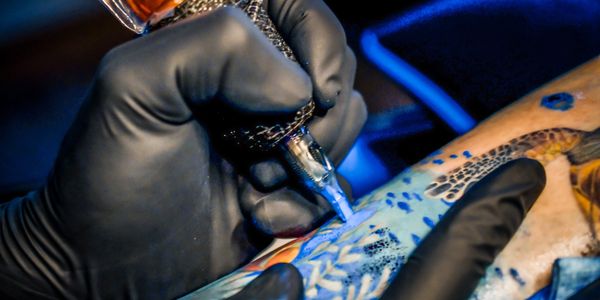 Close-up of a tattoo artist working with a tattoo machine.