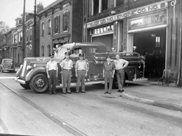 Black and white photo of firefighters with a vintage fire truck.