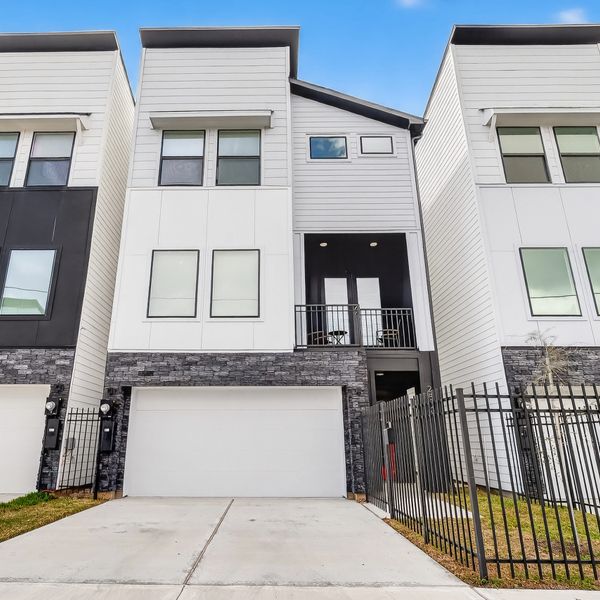 Modern three-story townhouse with a garage and balcony.