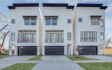 Modern white three-story townhouses with black garages and windows.