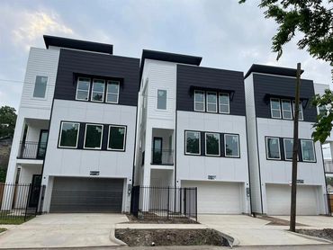 Modern three-story townhouses with white and black exterior and large windows.