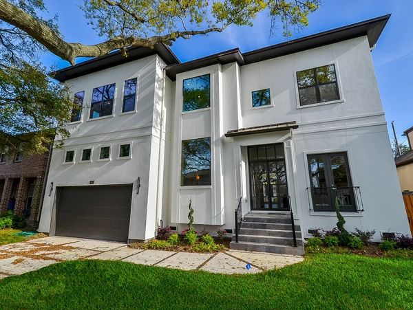 Modern two-story white house with large windows and a dark garage door.