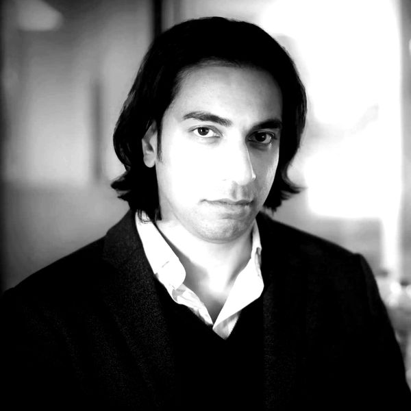 Black and white portrait of a man with medium-length hair in formal attire.