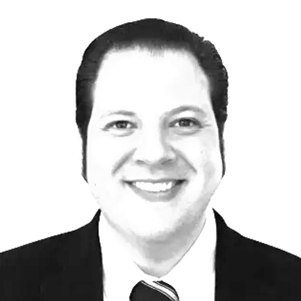 Black and white portrait of a smiling man in a suit and tie.