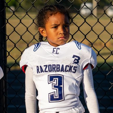 Young football player in Razorbacks jersey with serious expression.