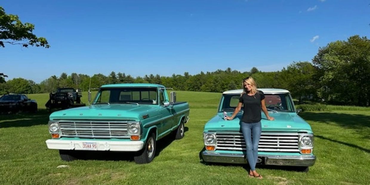 Two vintage turquoise Ford trucks with a woman posing on one.