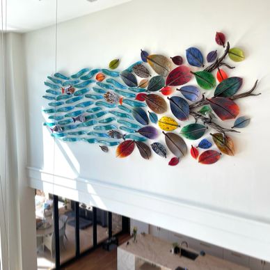 Custom wall piece of individually hung waves, fish, branches, leaves and a bird in a client's home
