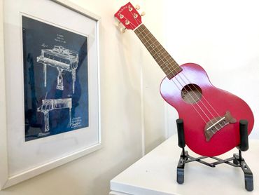 Ukulele standing next to patent diagram of a piano