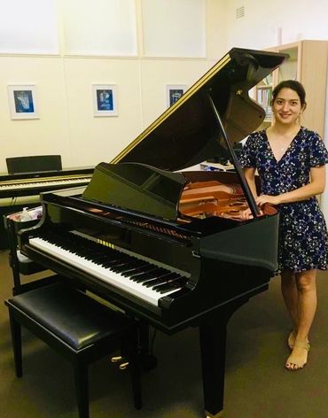 Music therapist, Speech pathologist and Piano teacher Robyn standing next to Grand Piano