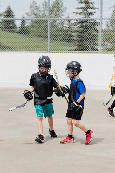 Two boys in hockey gear playing on an outdoor rink.