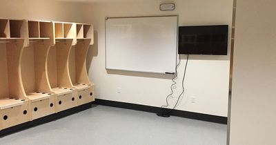 Empty sports locker room with wooden lockers and a whiteboard.