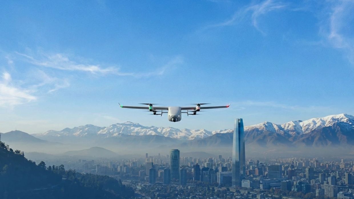 Drone flying over a city with snowy mountains in the background.