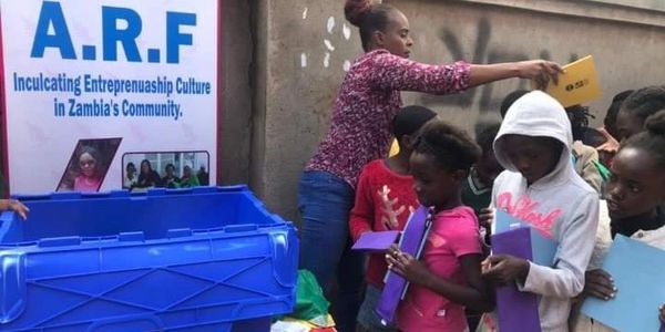 Children receiving educational materials at a community event in Zambia.