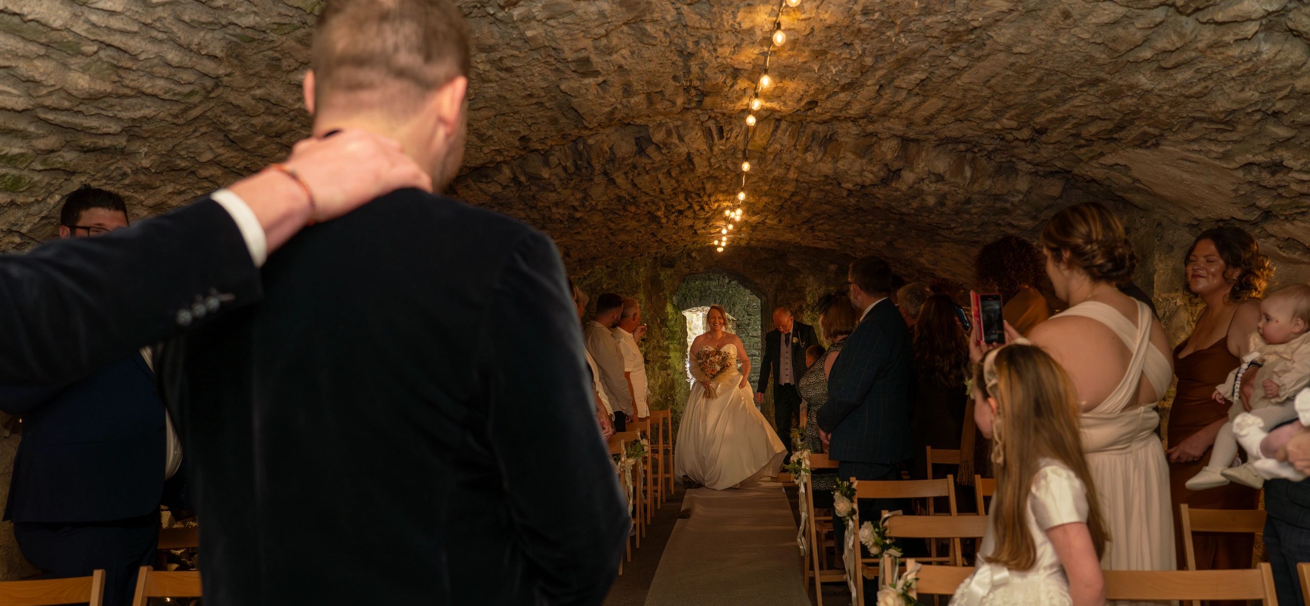 Documentary wedding photography bride walks down aisle towards waiting groom Wales Castle