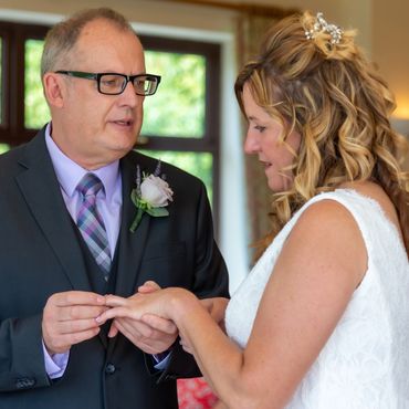 Wedding photograph of the groom placing the ring on his brides finger.  Beautiful wedding photograph