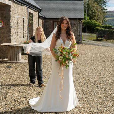 Documentary wedding photography bride holding wedding bouquet lady smoothing brides veil