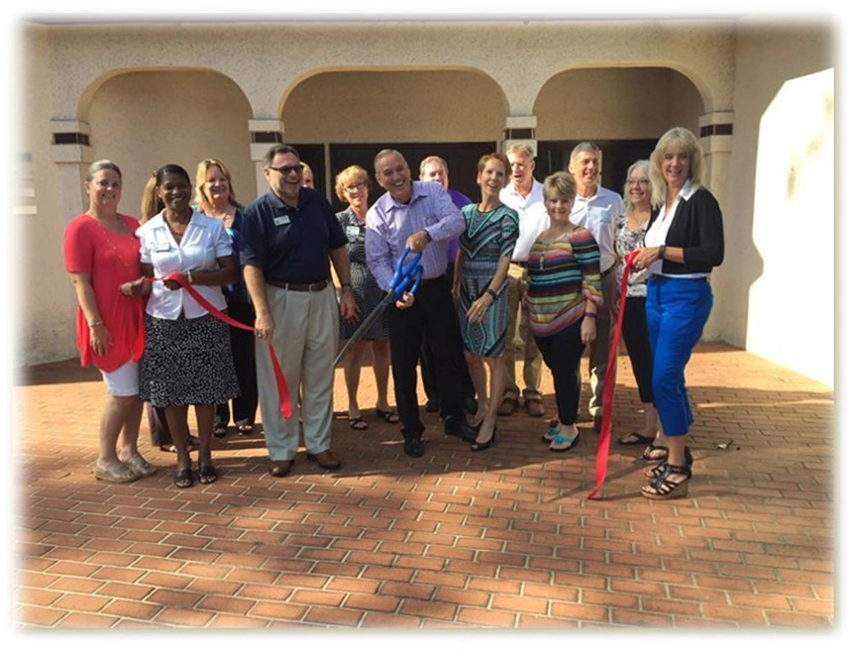 Group of people gathered for a ribbon-cutting ceremony outdoors.