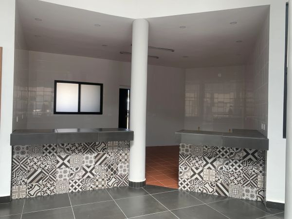 Área con dos mostradores decorados con azulejos y una columna central.