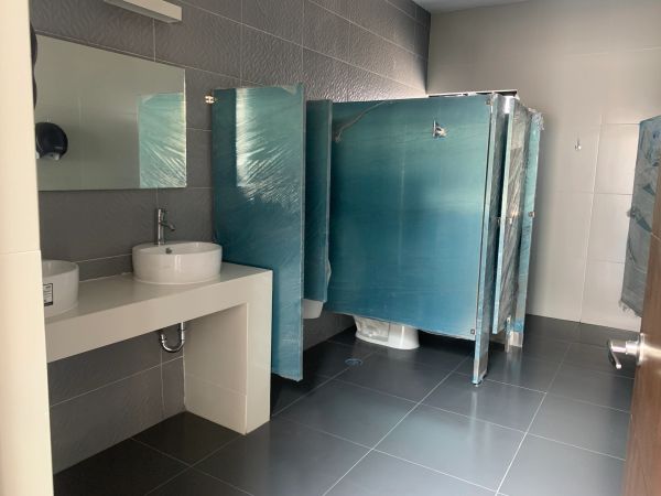 Baño con lavamanos y cubículos cubiertos de plástico.